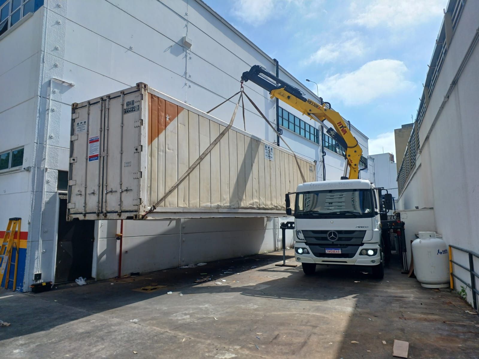 Içamento de container refrigerado com caminhão munck em espaço reduzido