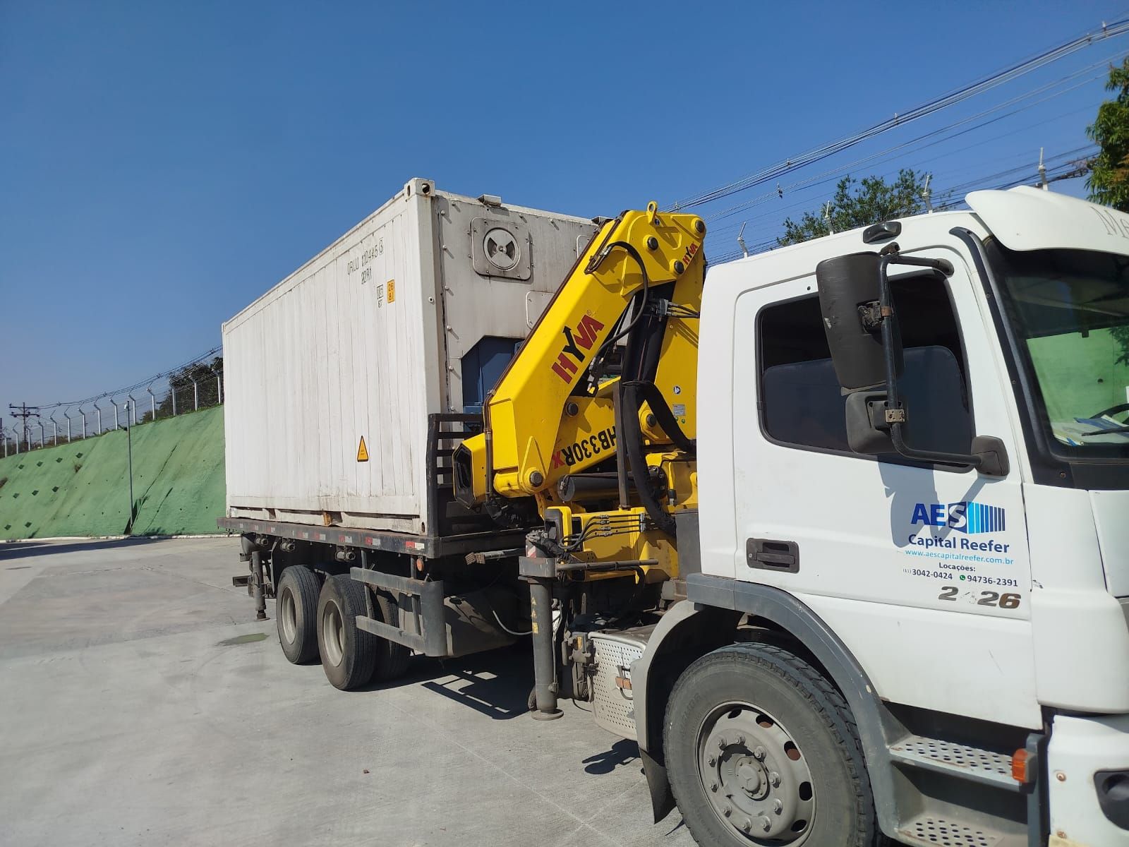Caminhão munck da AES Capital Reefer transportando container refrigerado de 20 pés